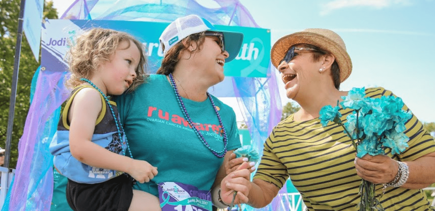 Two women laughing, one holding a child